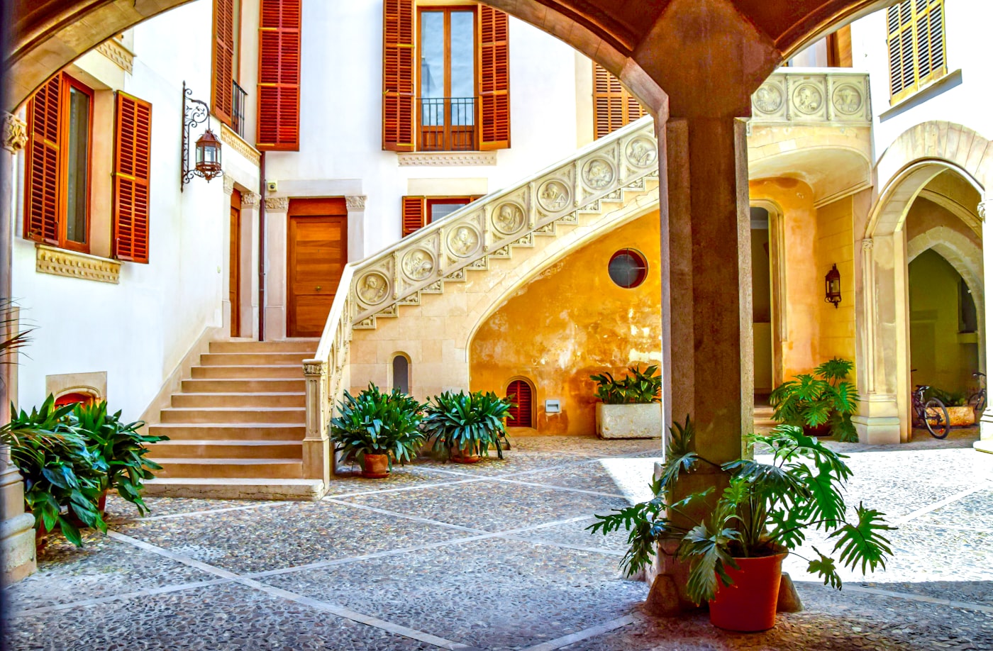 Sunlit courtyard and stone staircase of a boutique hotel